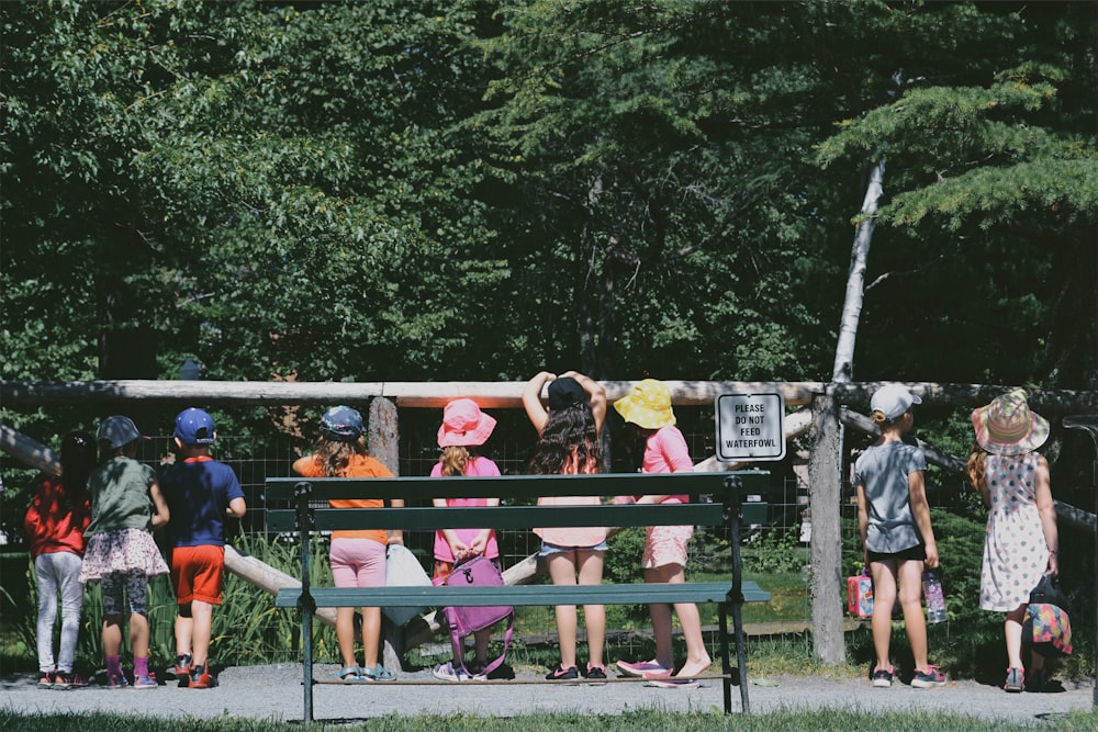 enfants debout à côté de la clôture pendant la journée