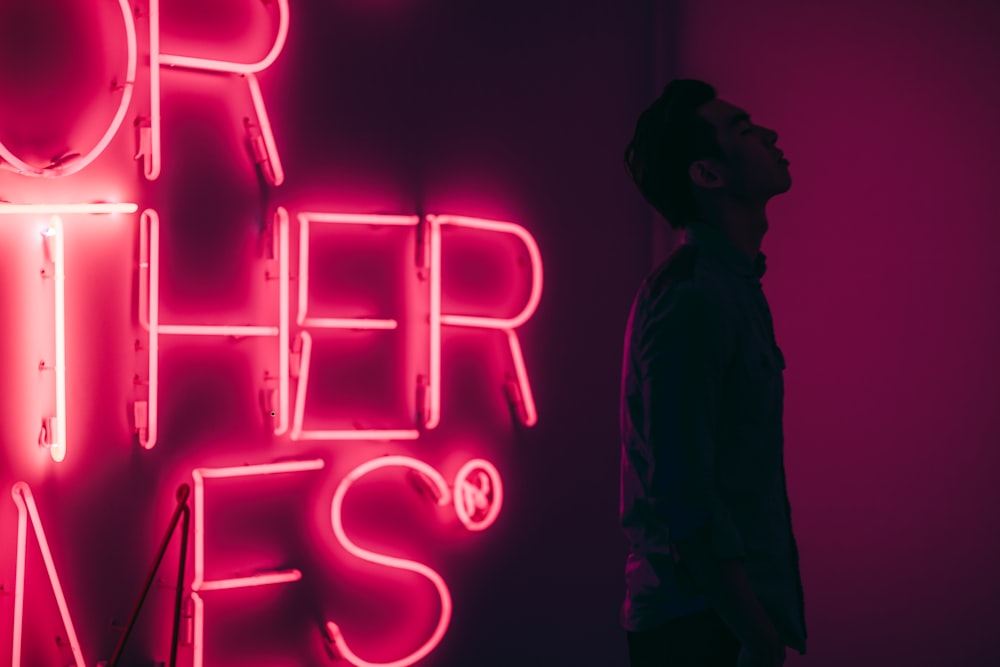 man standing beside red LED signage