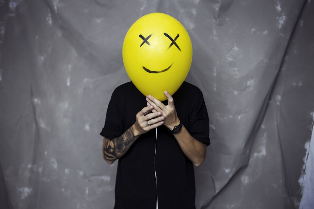 person wearing black shirt holding yellow and black balloon