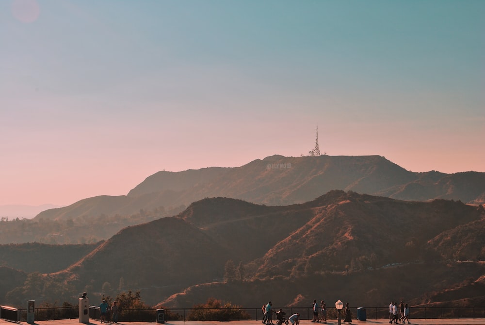 people standing and walking on pathway with green mountain at distance