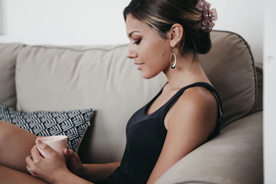 A smiling woman enjoying a peaceful morning with a cup of tea, embodying calm and confidence.