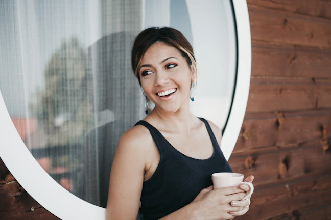 Lifestyle shot of a joyful person holding cutu products against a bright window.