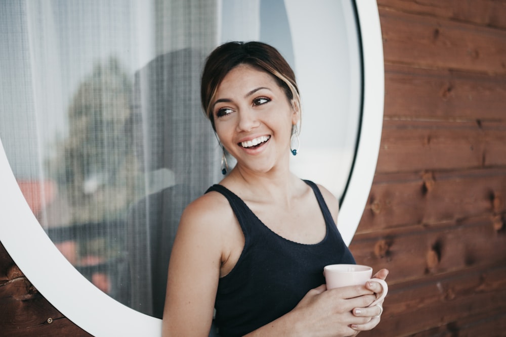 donna che indossa una canotta nera che tiene la tazza