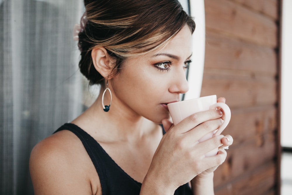 Frau lehnt sich an die Wand und trinkt Kaffee