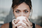 woman drinking from white coffee cup