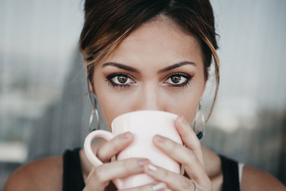 mujer bebiendo de taza de café blanco