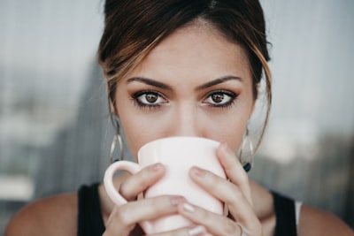 woman drinking from white coffee cup intense google meet background