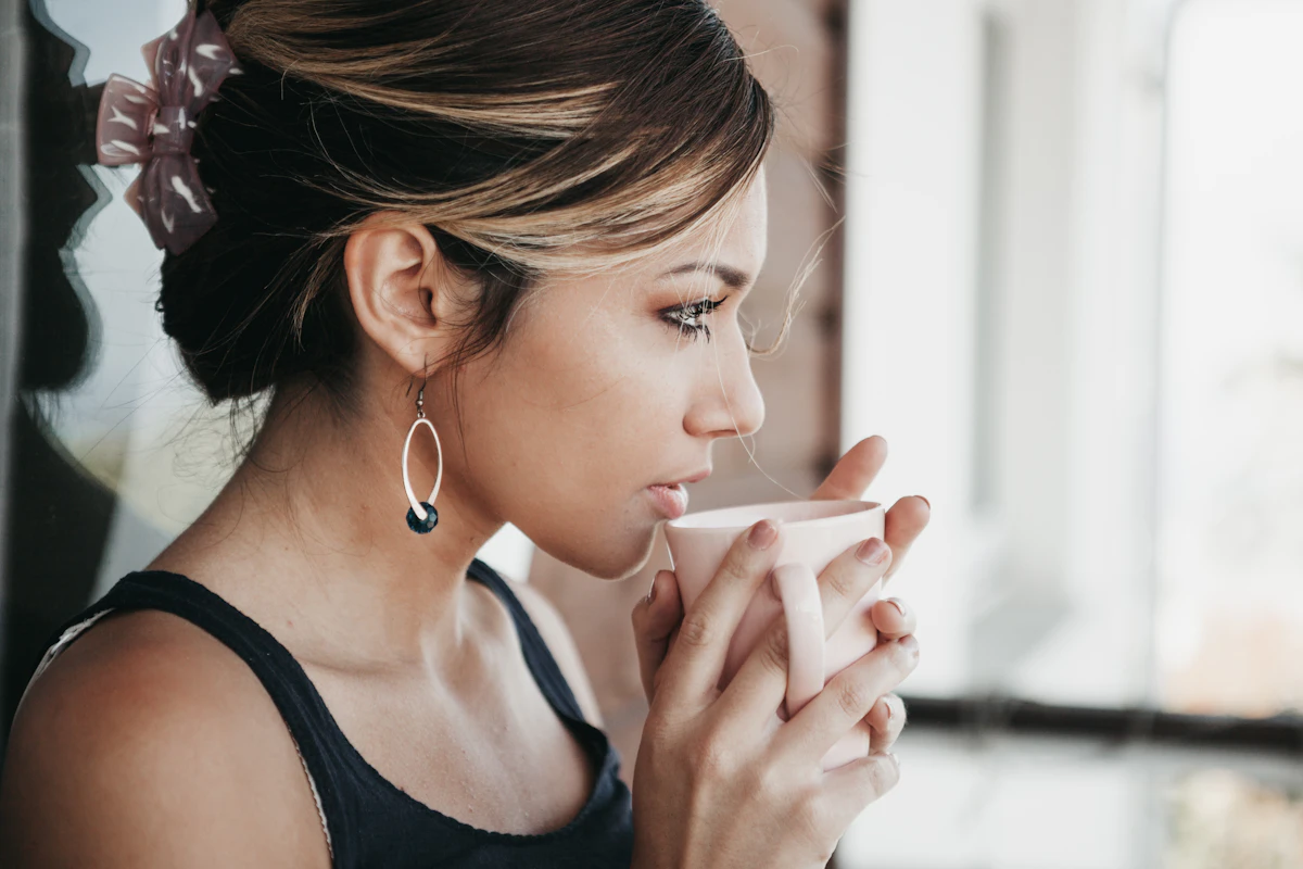 A woman holding a warm cup, taking a quiet moment for her wellbeing