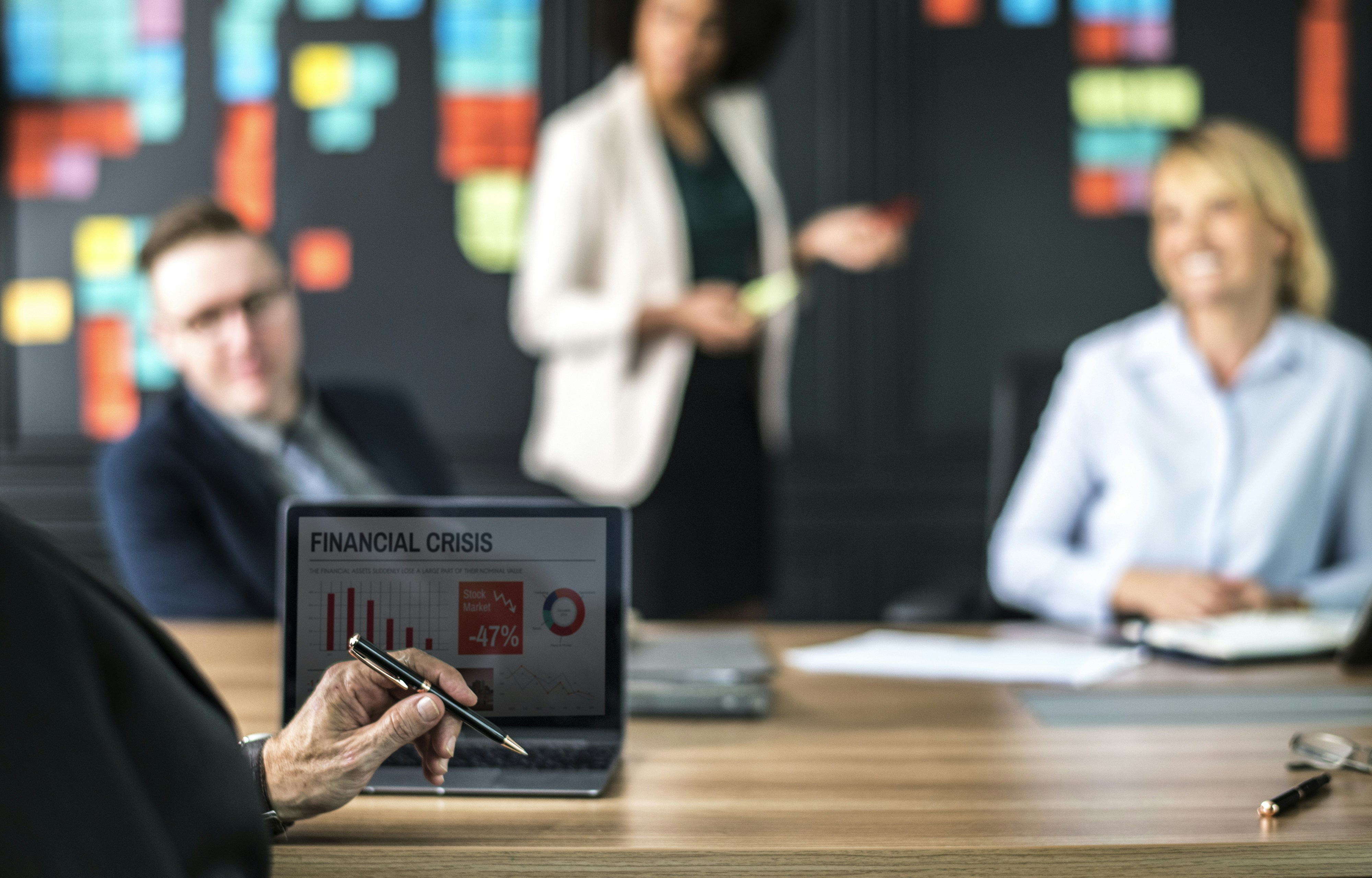 Photograph of five business people surrounding a laptop.