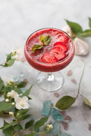 clear wine glass surrounded by leaves on table