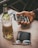 A hand is holding a smartphone displaying a social media app with images. A bottle of beer with a filled glass sits next to a black wallet and a pair of glasses on a wooden table.