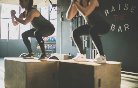 two ladies jumping on boxes in a gym