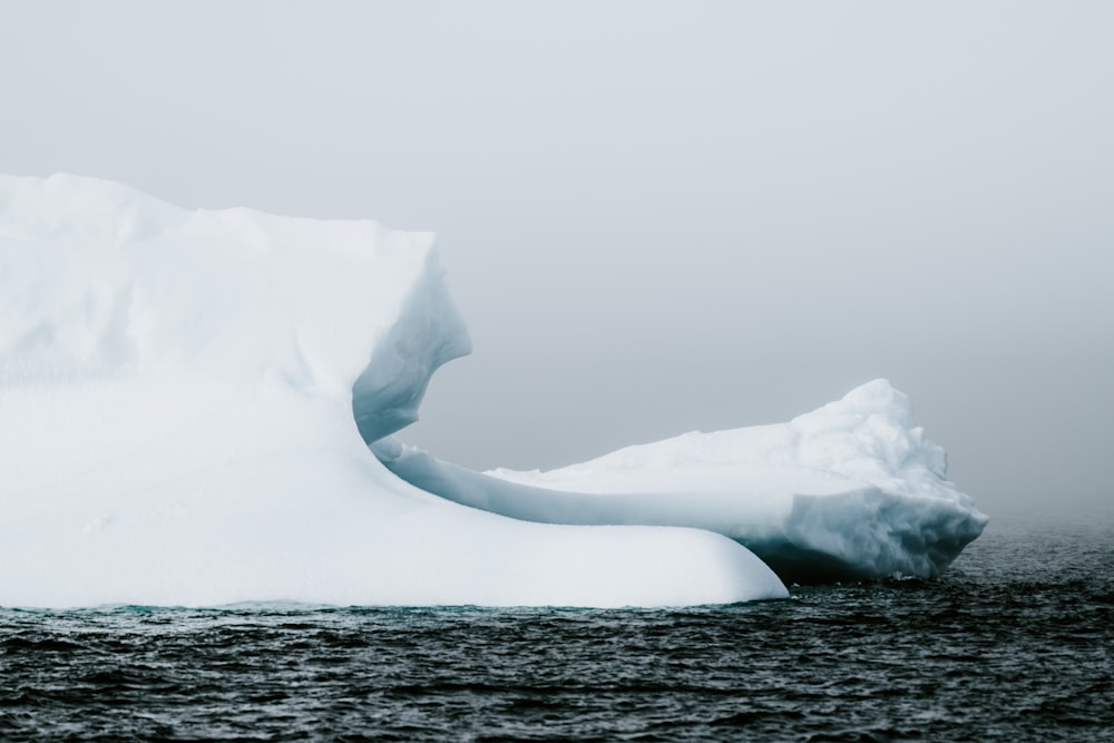 iceberg on sea under dark cloud