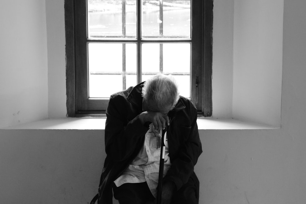 man sits on chair near window