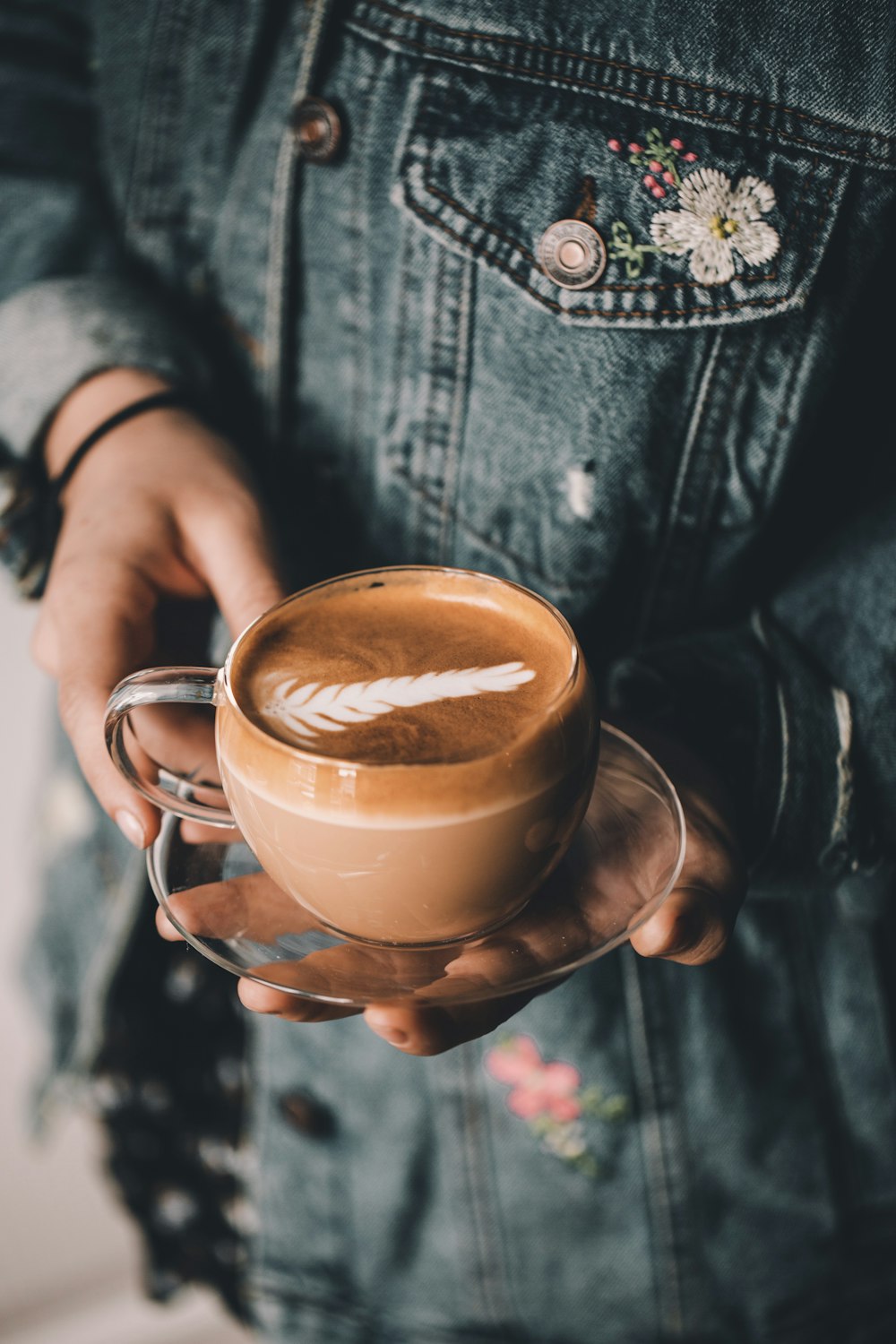 person holding clear teacup on saucer