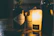 A close-up of a golden gin bottle with a warm, inviting glow in a cozy bar setting.