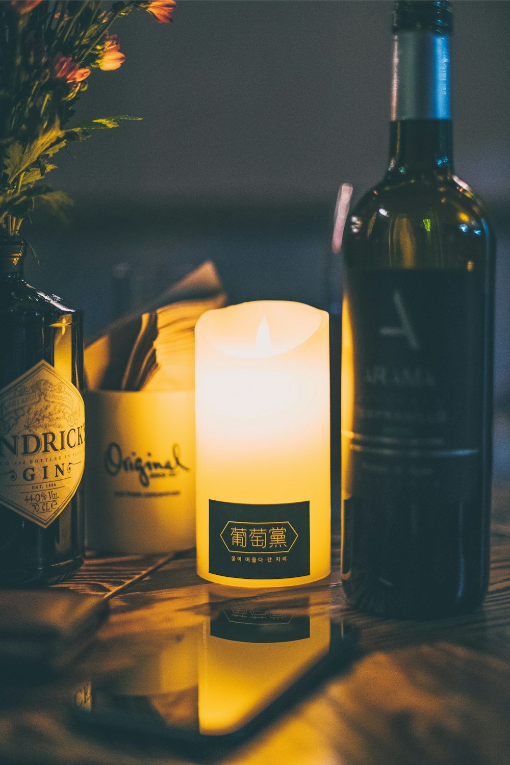 white pillar candle beside wine bottle