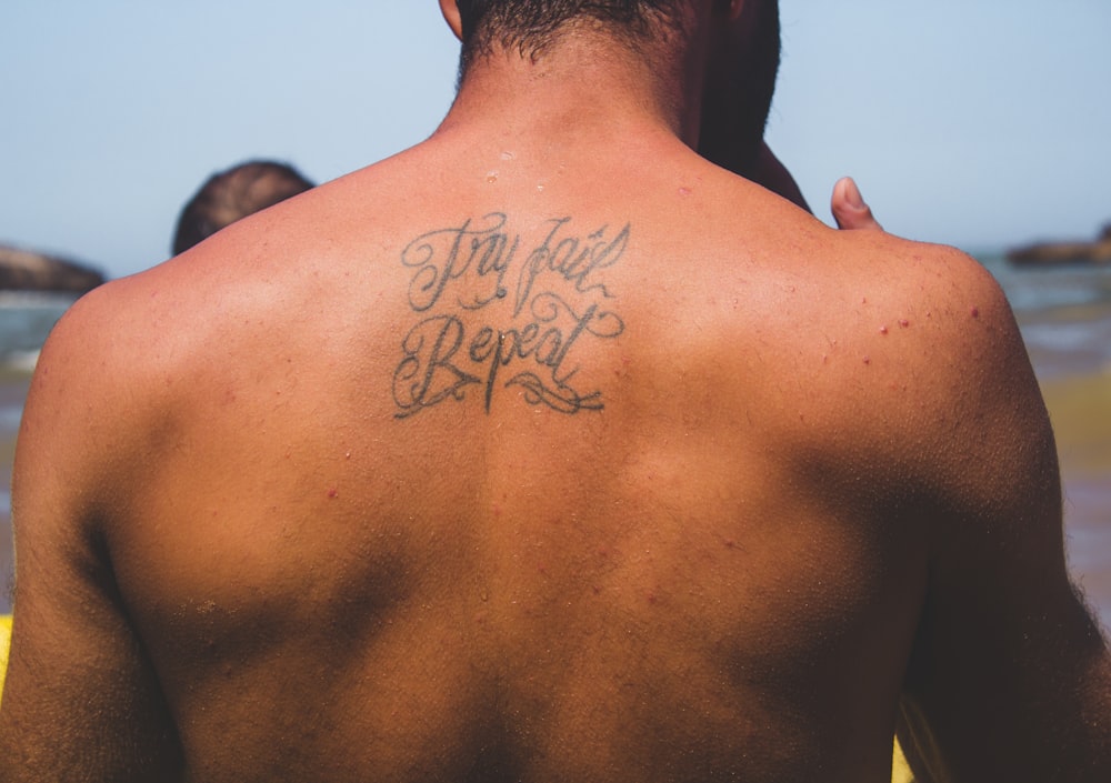 person with try fail repeat tattoo at back