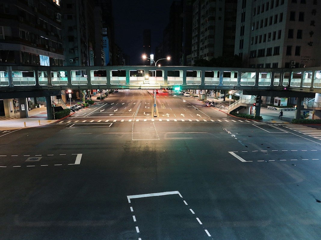 夜晚的台北大路口與地面白色框線標線，上方有人行陸橋