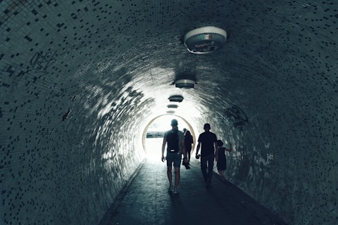 people walking under tunnel