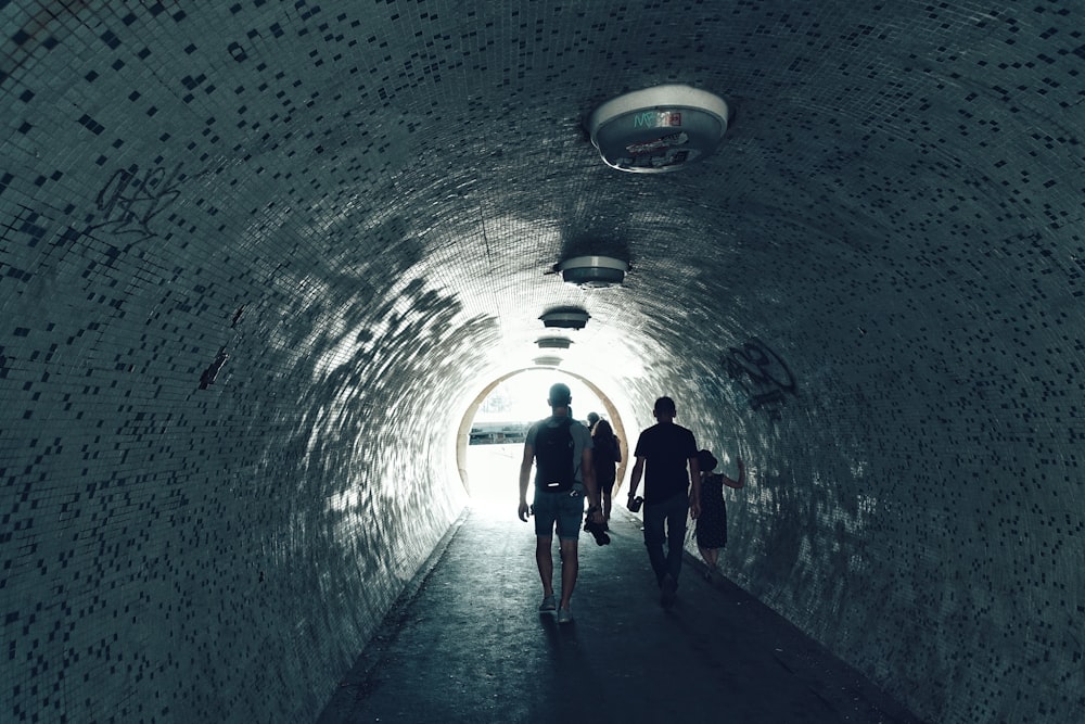 people walking under tunnel