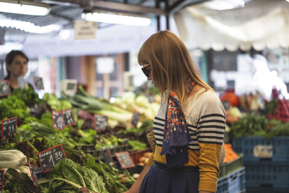 Femme debout devant les légumes au marché pendant la journée