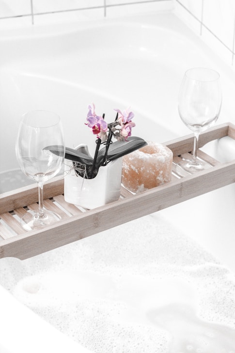 a clean bathtub with two wine glasses on tray