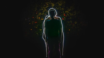 A silhouette of the model with glowing white eyes framed by a tangle of black branches.