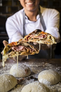 A friendly chef tossing pizza dough in the air, smiling in a modern kitchen.