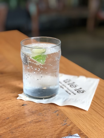 Close-up of a clear glass filled with sparkling mineral water on a wooden table.