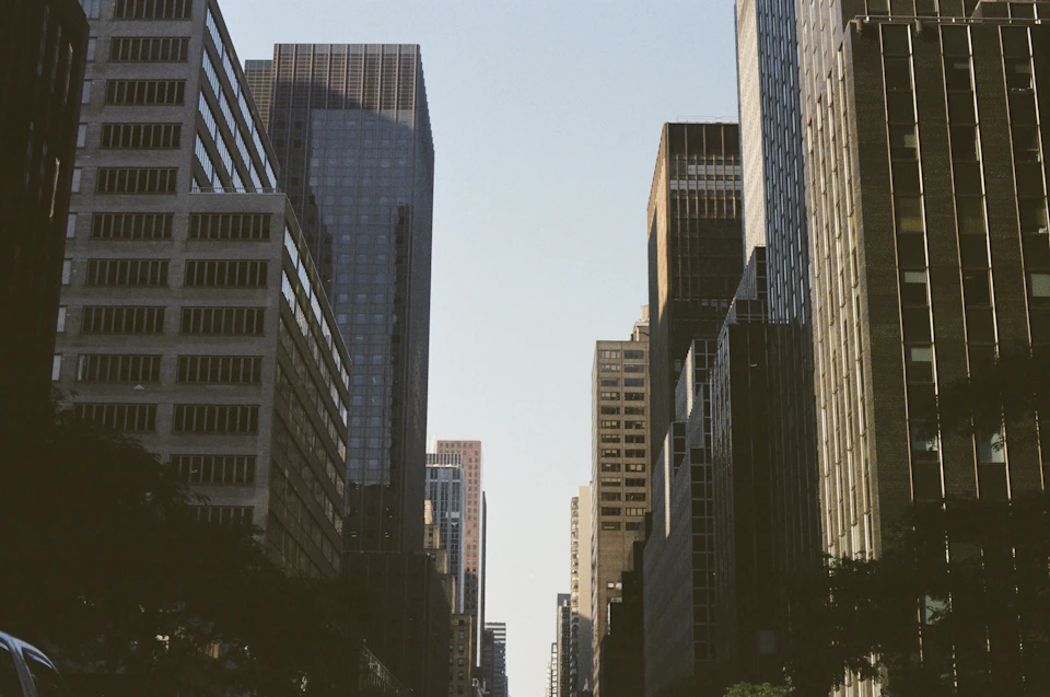 Tall, modern buildings stretch towards the sky in a bustling city street scene