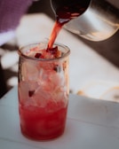 A vibrant mix of the tonic being poured into a glass, glowing with rich red tones.