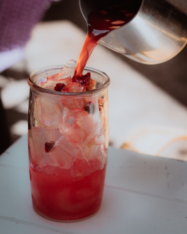 A vibrant splash of Enemy Ender soft drink pouring into a glass filled with ice.