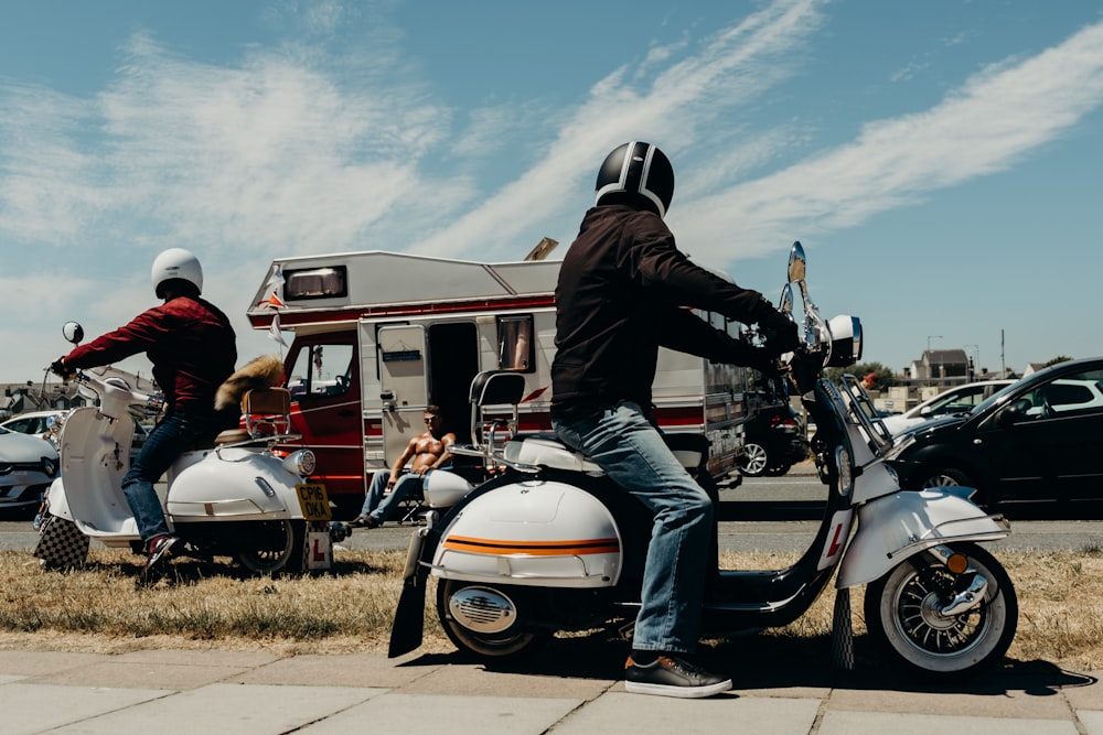 person riding white motor scooter near camper trailer