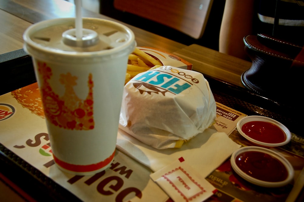 Foto von Burger King Burger neben Becher und Ketchup-Portion auf Tablett