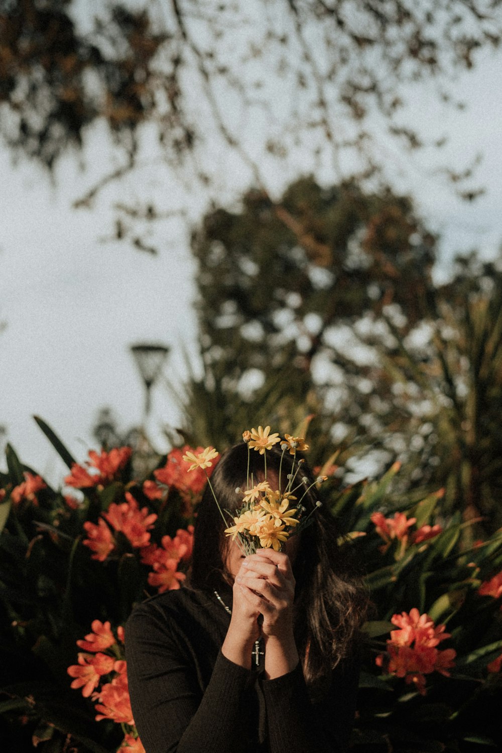 mulher escondendo seu rosto com flores amarelas durante o dia
