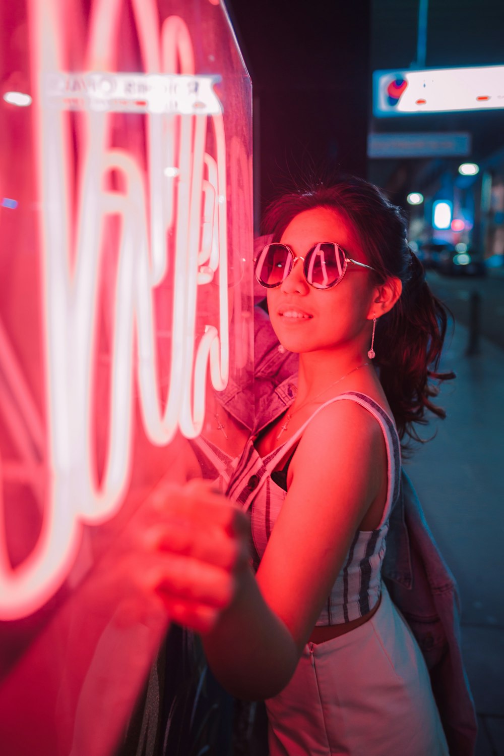 woman standing near red neon signage at night