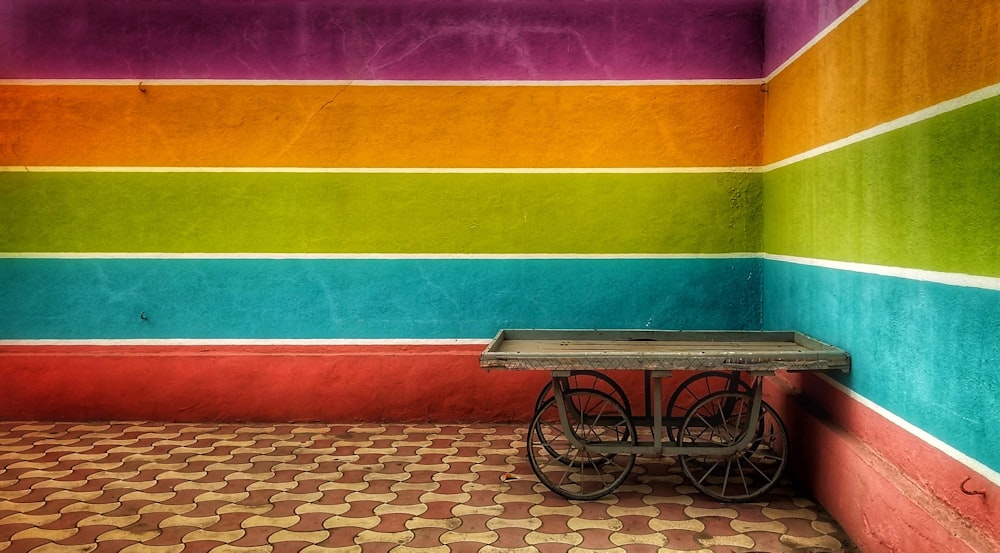 brown wooden bicycle cart near multicolored paint wall
