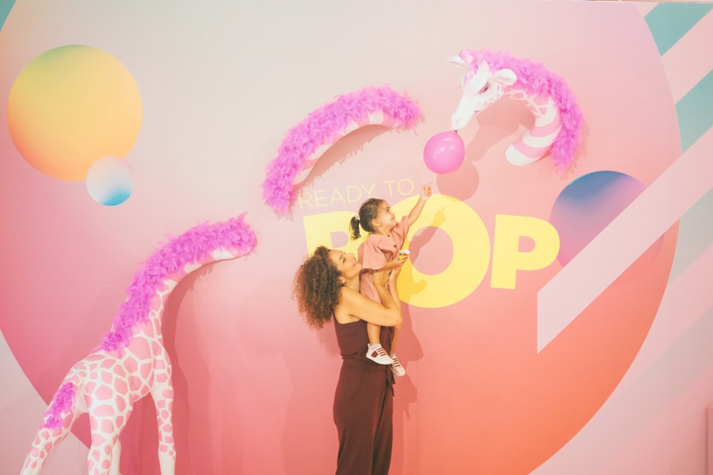 woman carrying girl holding balloon