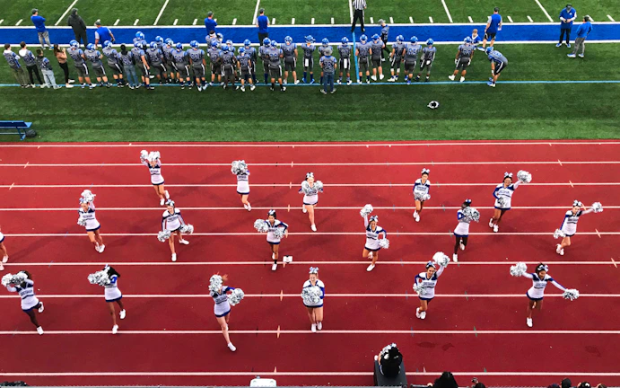 Coaches cheering on a diverse team of runners during a spirited practice session