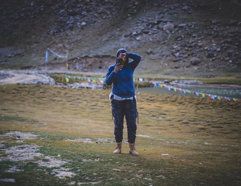 person in blue jacket and pants holding phone taking picture