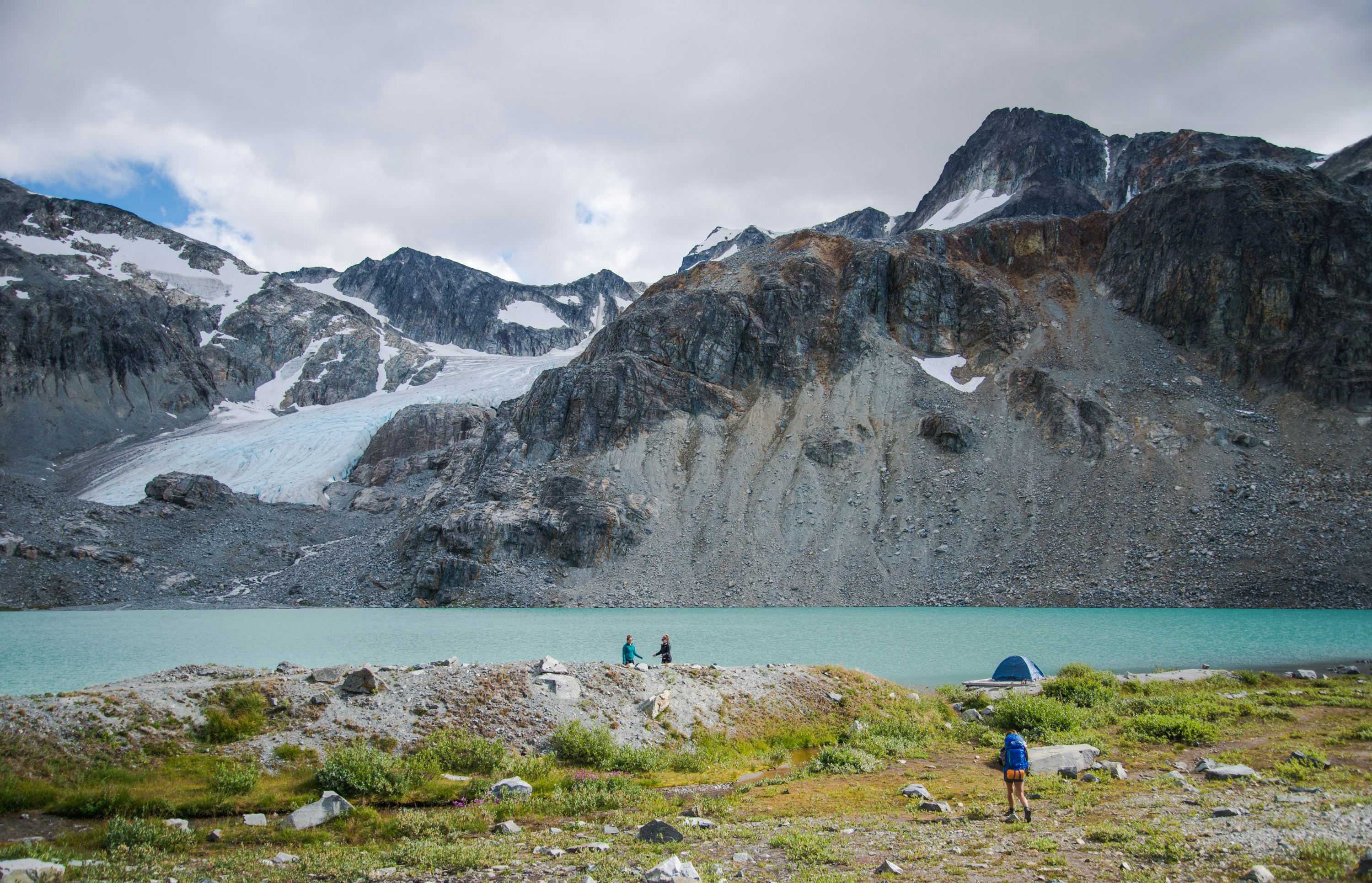 people near lake overlooking mountains