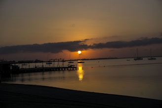 A serene view of sailboats docked at Bear Lake Yacht Club with mountains in the background during sunset.