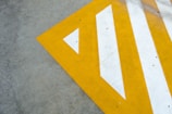 A concrete surface features a large, angular yellow and white painted pattern forming a triangular design with stripes.