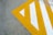 A concrete surface features a large, angular yellow and white painted pattern forming a triangular design with stripes.