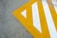 A concrete surface features a large, angular yellow and white painted pattern forming a triangular design with stripes.