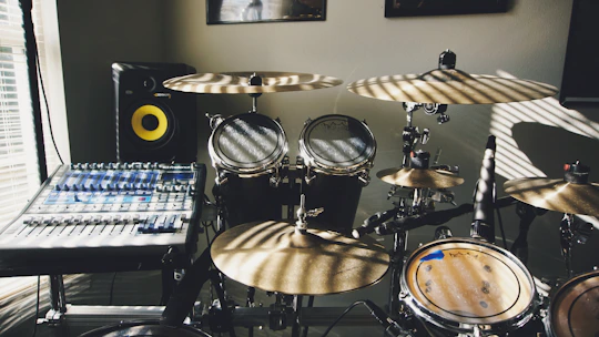 A collection of drum pads and audio mixers arranged on a wooden table.