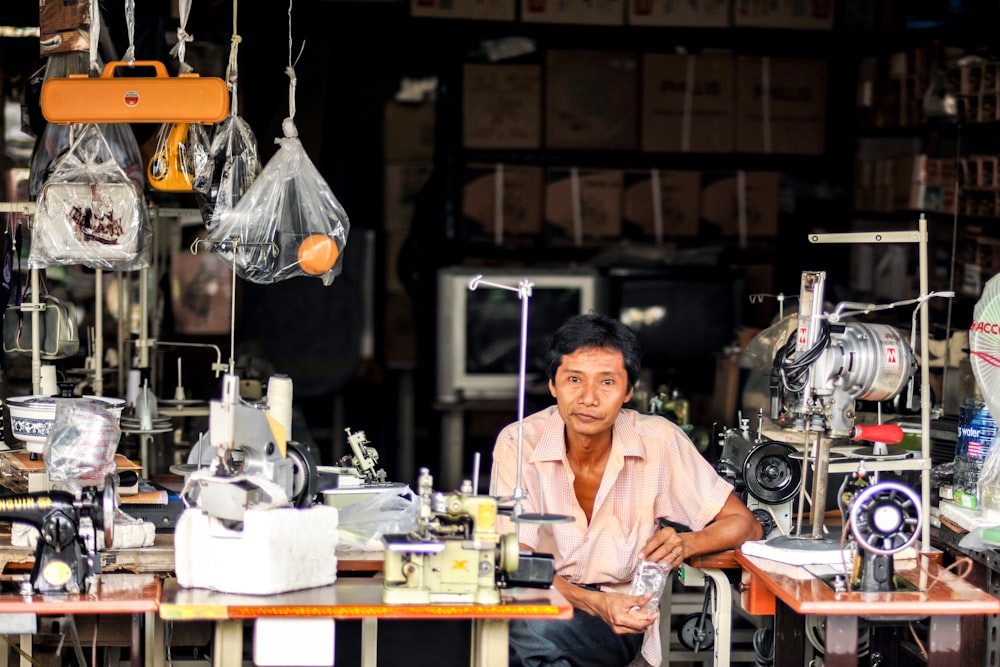 man sitting between two sewing machines