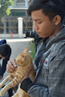 A volunteer gently holding a rescued cat outdoors.