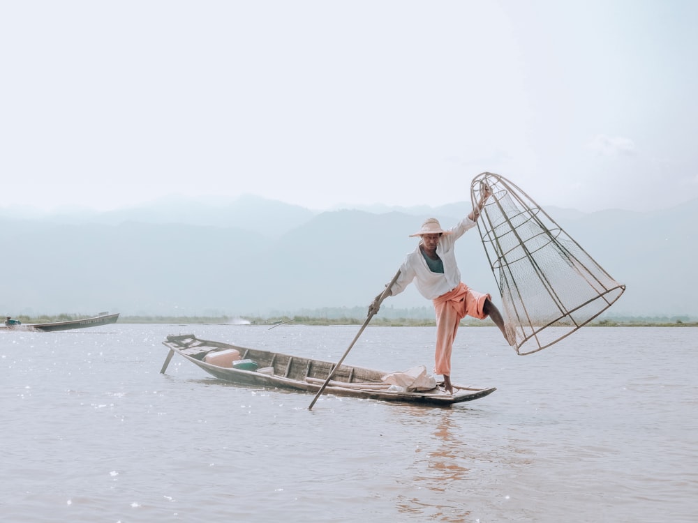 person holding fishnet standing on boat during daytime